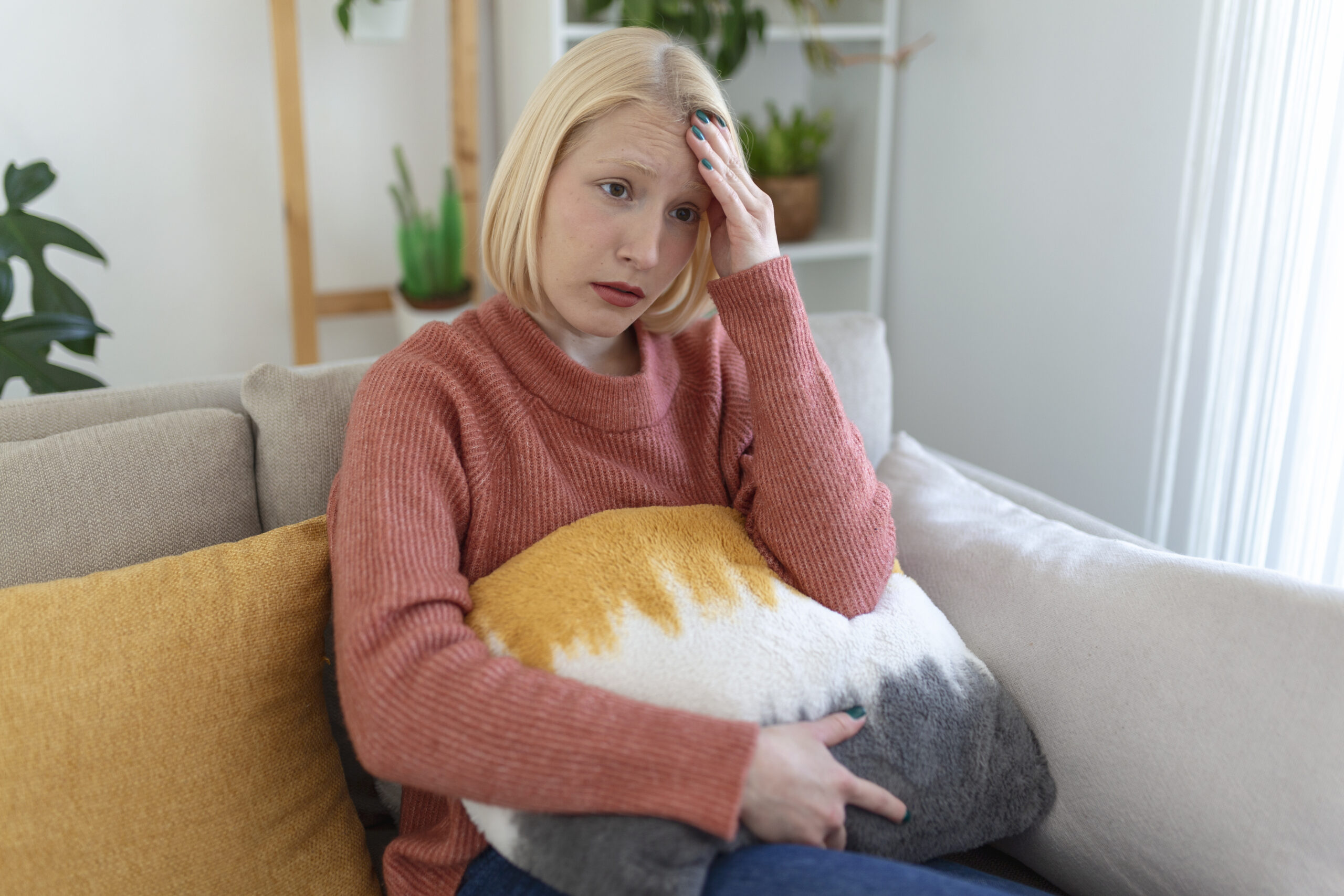 portret-mlodej-blond-kobiety-siedzacej-na-kanapie-w-domu-z-bolem-glowy